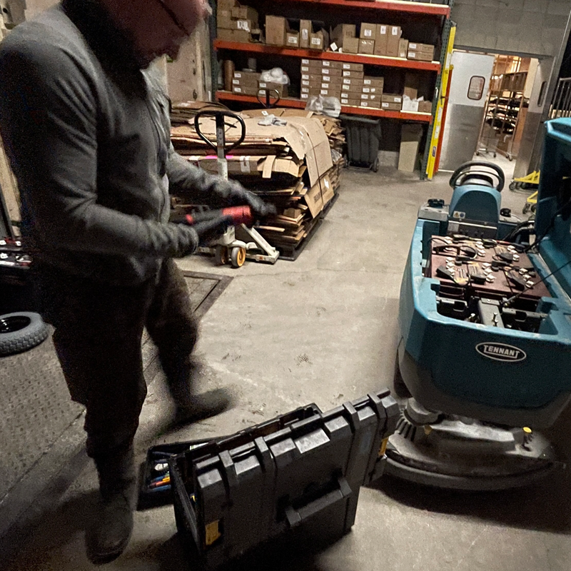 Technician repairing a Tennant T6 100i floor cleaning machine inside the dedicated cleaning room at Steadfast Maintenance & Repair LLC, showcasing expert service and commercial equipment care.